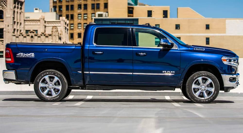 A blue 2021 Ram 1500 Limited is shown from the side parked in an empty lot.