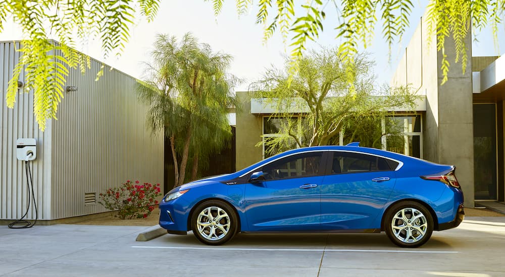 A blue 2016 Chevy Volt is shown from the side parked near a charger.