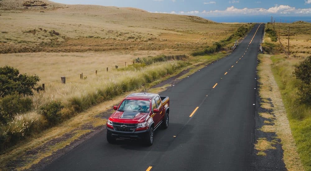 A red 2021 Chevy Colorado ZR2 os shown driving down an empty road.