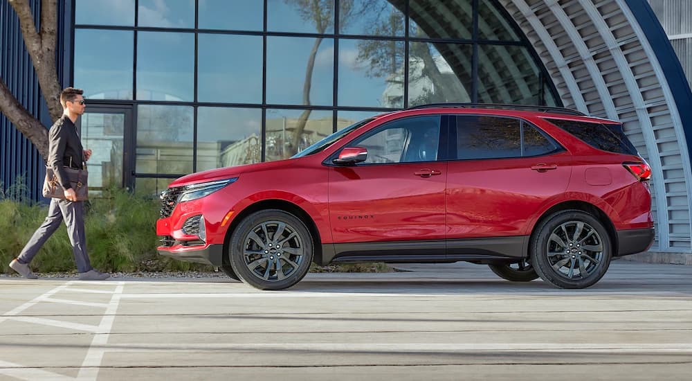 A red 2022 Chevy Equinox RS is shown from the side outside of a modern building.